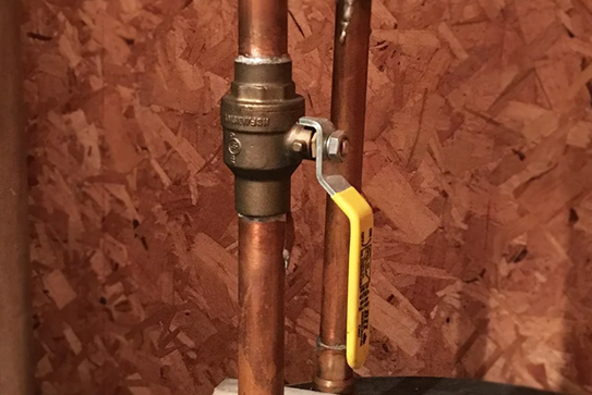 Robinet en cuivre avec levier jaune.