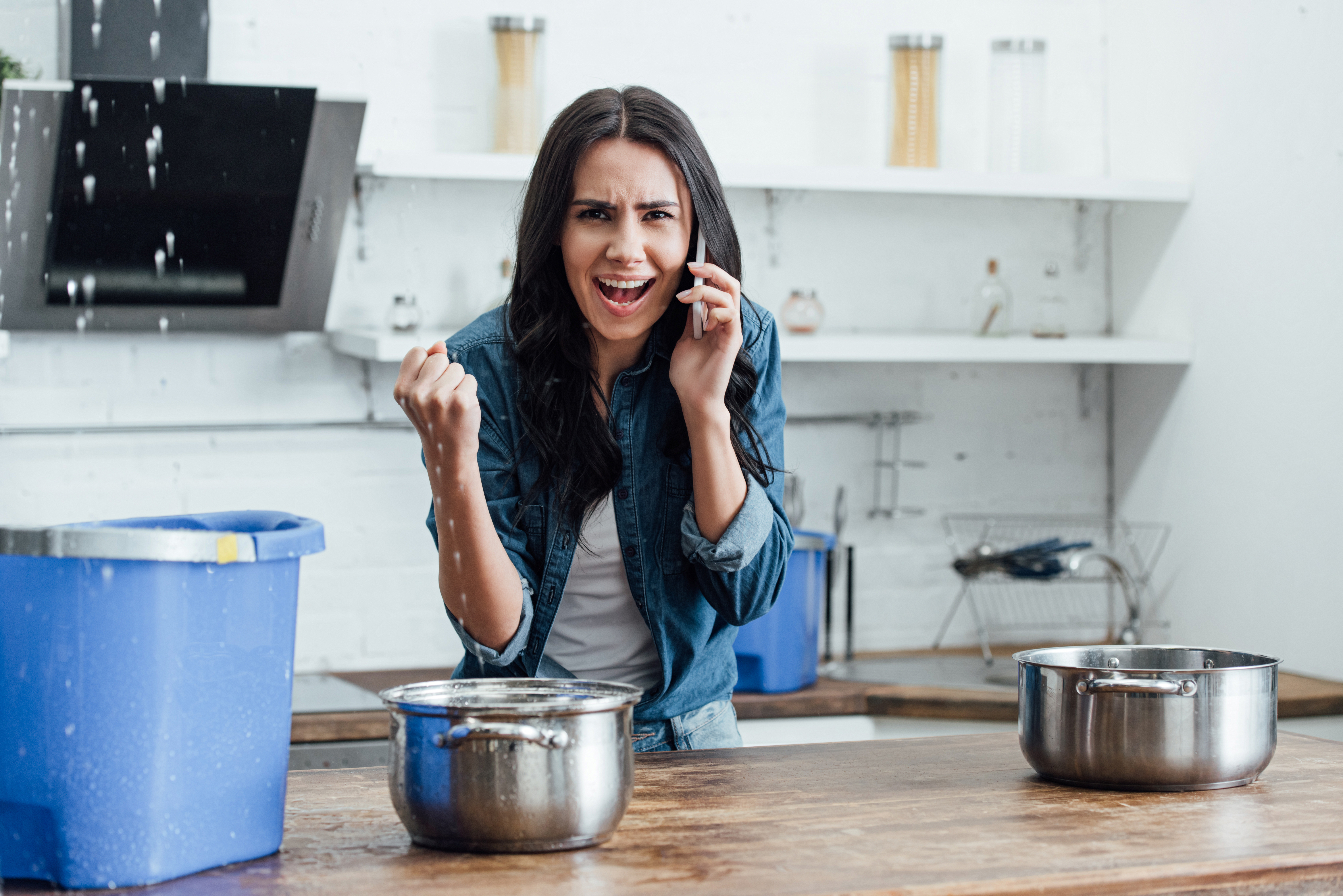 Femme appelant à l'aide pour fuite d'eau cuisine.