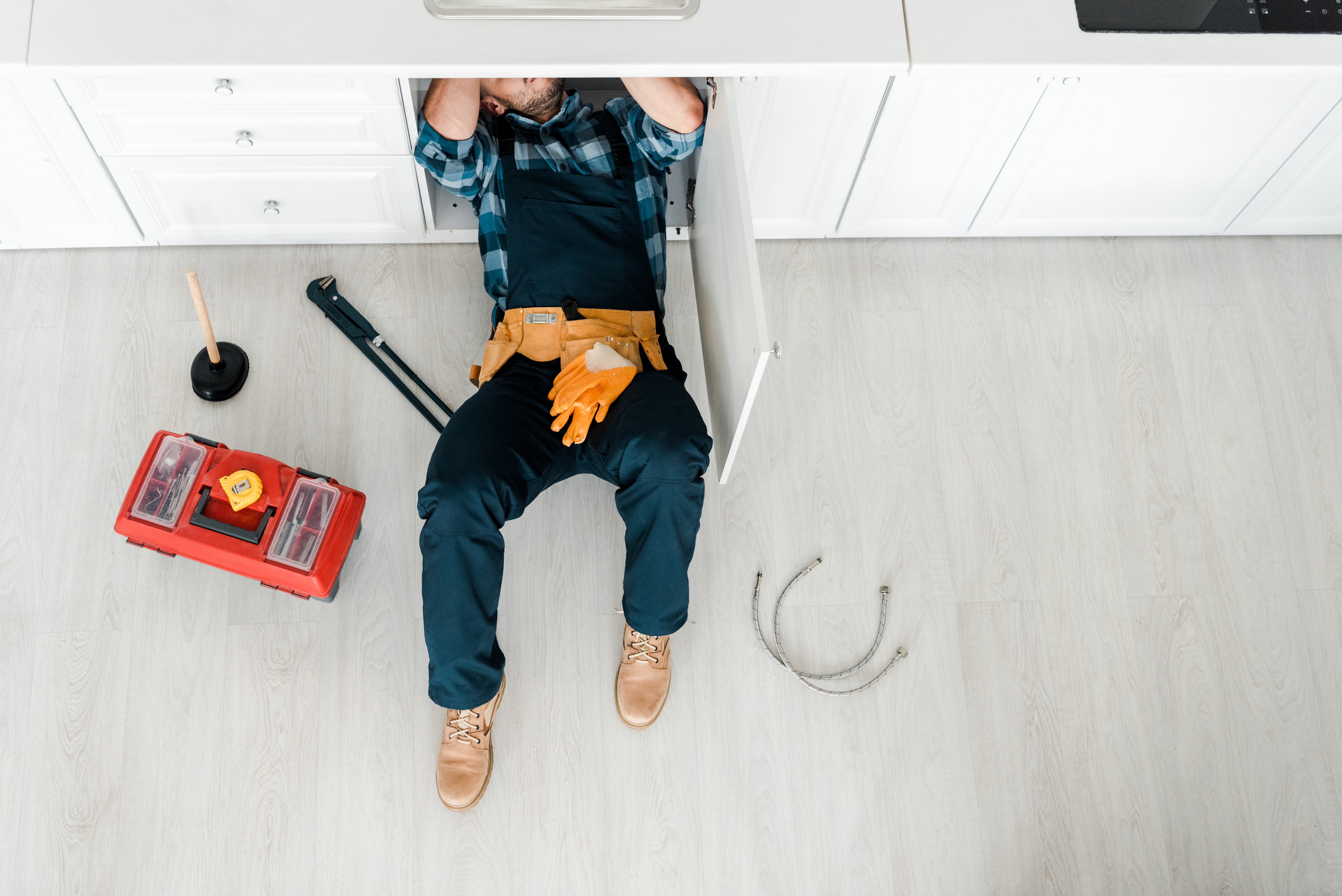 Plombier réparant évier avec outils sous le comptoir