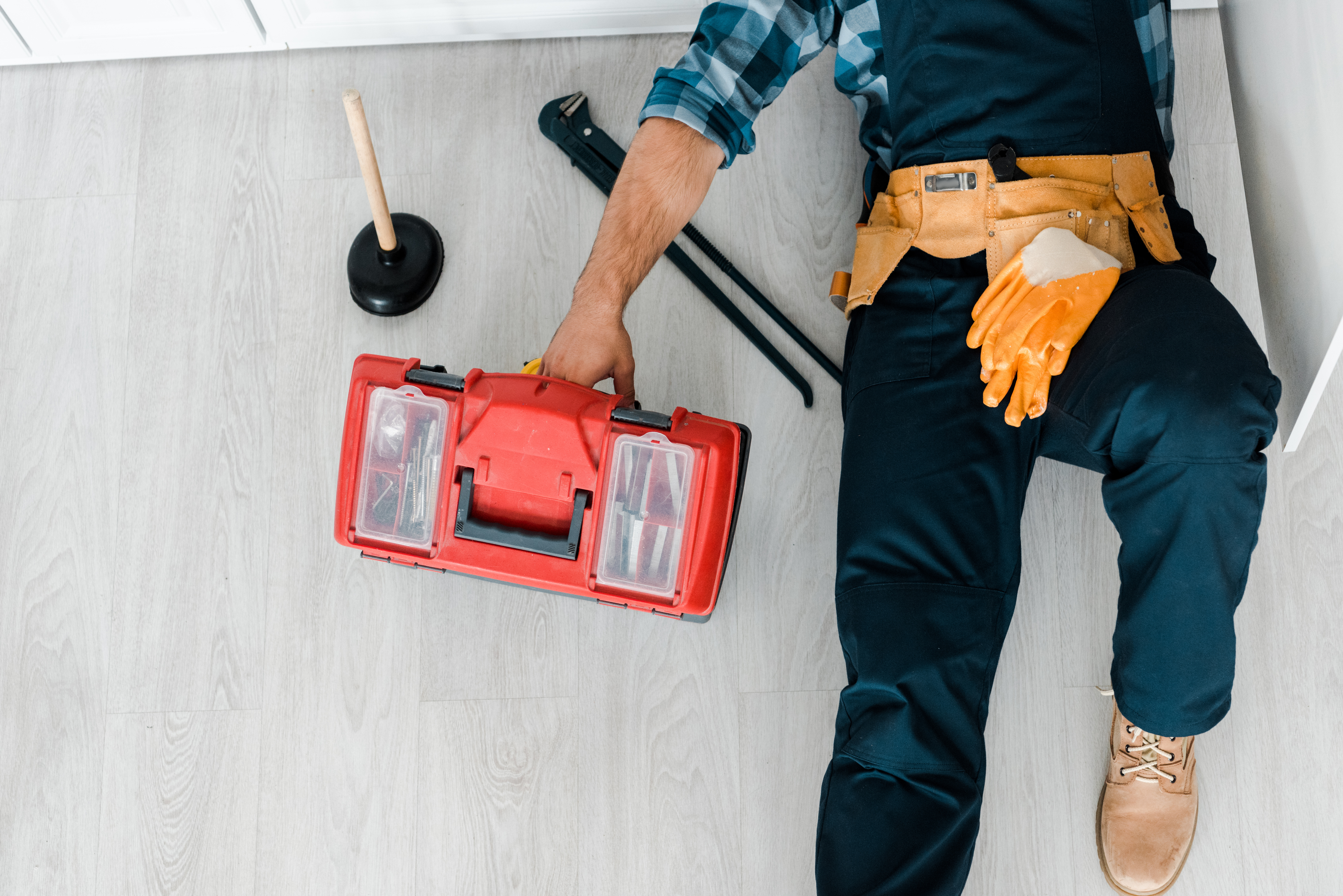 Travailleur tenant une boîte à outils rouge.