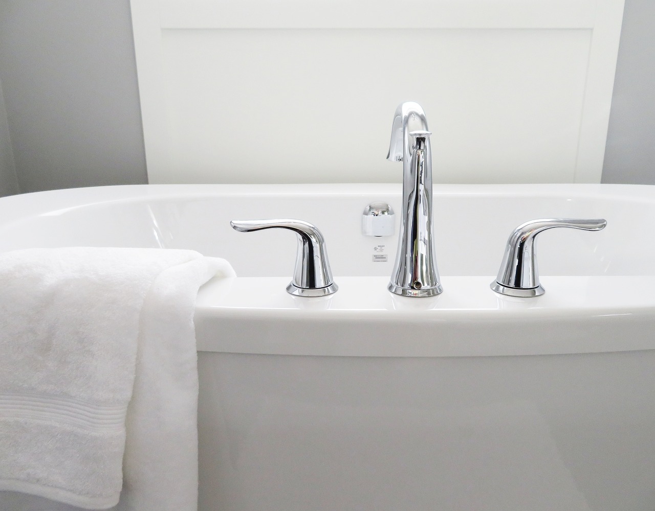 Baignoire moderne avec robinet chromé et serviette blanche.