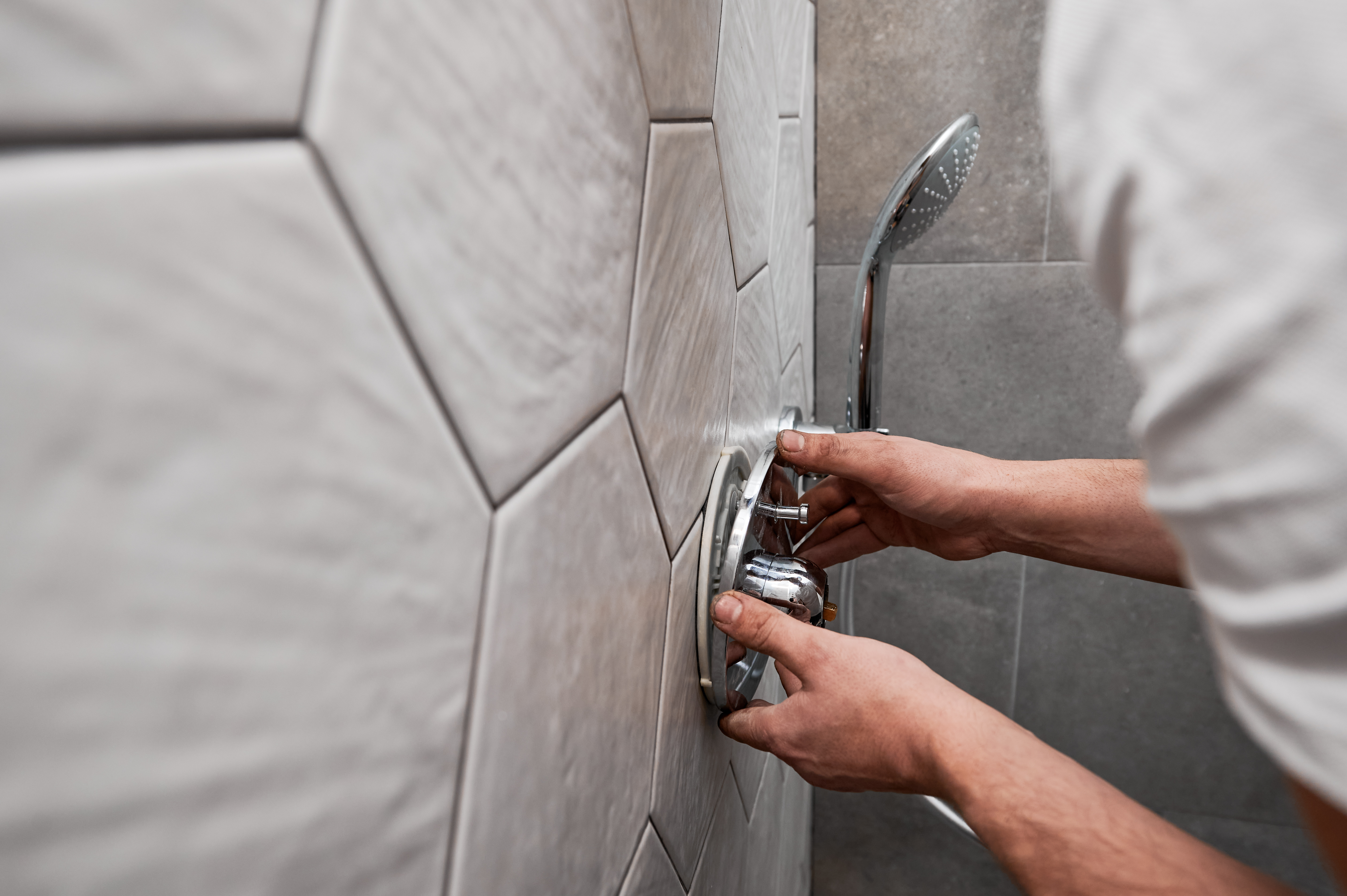 Personne réglant robinet de douche moderne sur carreaux.